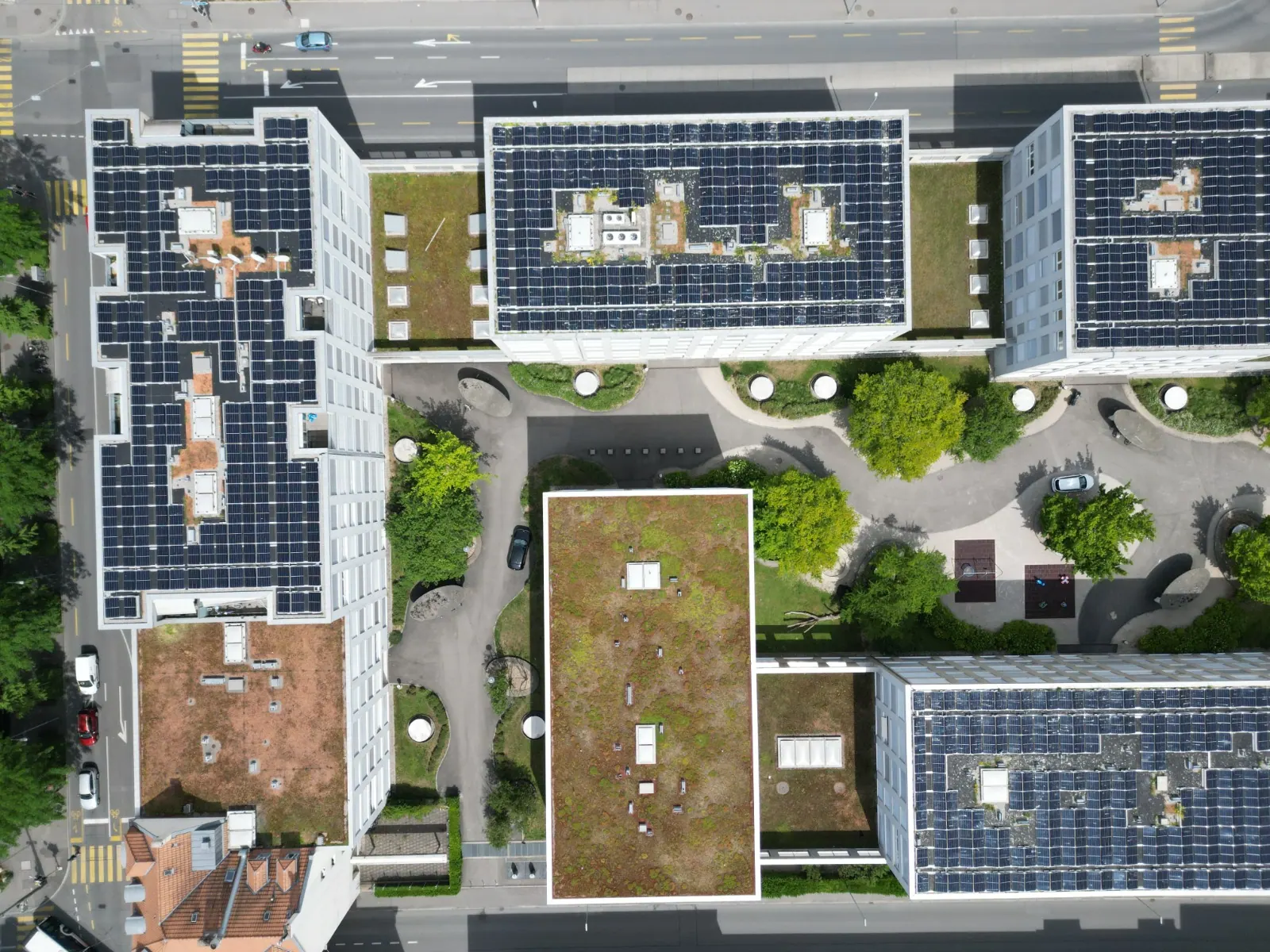 Drohnenaufnahme von oben: mehrere Wohnbauten um einen Hof mit Photovoltaik auf den Flachdächern