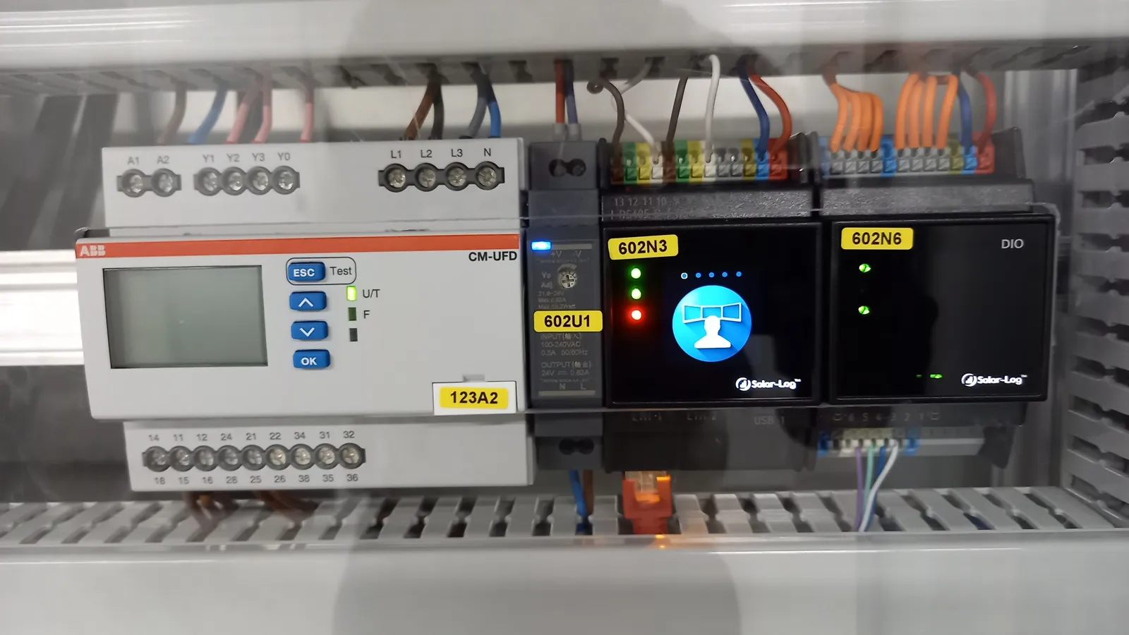 Solar-Log-Geräte mit leuchtendem Display in einem Schaltschrank, daneben ein Überwachungsrelais